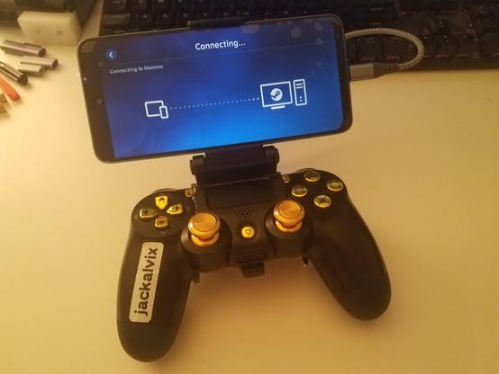 a ps4 controller with gold buttons and a phone mount. label reads "jackalvix". a phone is connected by a short cable, showing the Steam Link app.