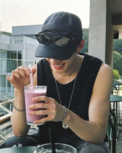 Bang Chan with a pink smoothie. He's wearing 2 Chrome Hearts bracelets and the Chrome Hearts cutout dog tag pendant on a chain.