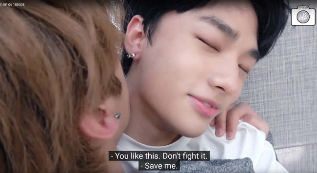 Hyunjin is lying on his back on the floor, filming a selfie-cam. Lee Know is lying on top of him, holding Hyunjin's shoulder from underneath, and moving his face close to Hyunjin's neck. Hyunjin has his eyes closed and is smiling. Caption: "You like this. Don't fight it." "Save me."