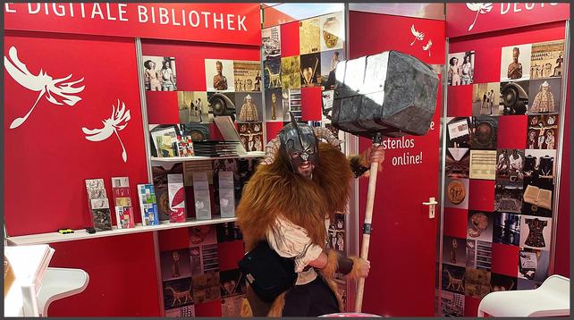 Cosplayer mit Fellumhang, Helm und riesigem, erhobenem Hammer