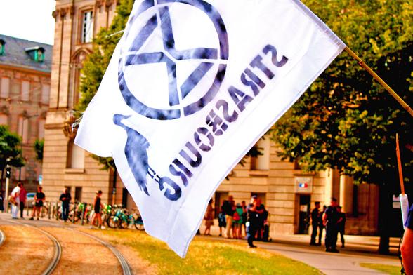 Drapeau "Strasbourg" avec le logo de Extinction Rébellion et une cigogne