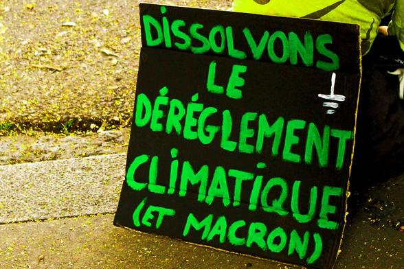 Pancarte avec de la peinture verte "Dissolvons le dérèglement climatique (et Macron)