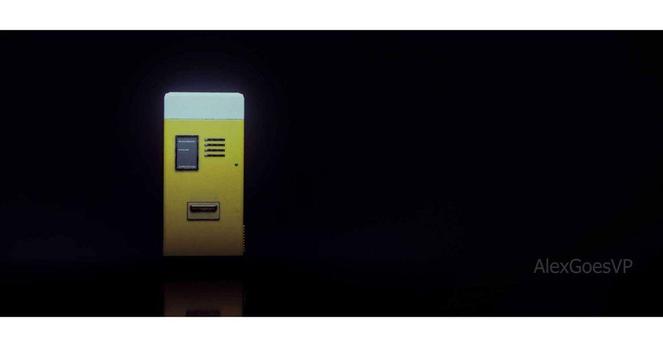 A yellow vending machine, with a white band on top, standing under the light in the otherwise complete darkness. It is lightly reflected on the dark floor.