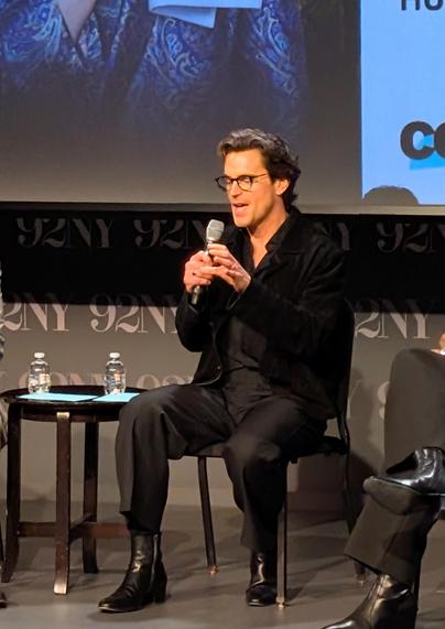 Matt Bomer speaking on stage, wearing all black