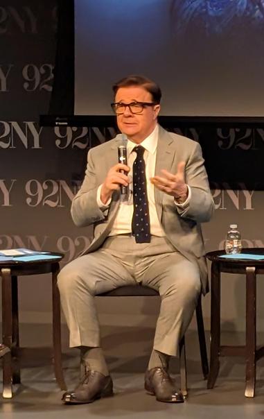 Nathan Lane speaking on stage, wearing a tan suit