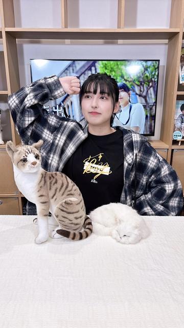 Maria at a table with two cat statues/plushies?