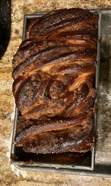 Glossy dark bread in a pan, viewed from the top