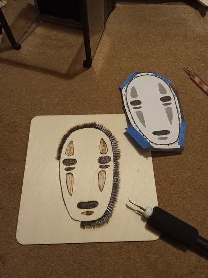 Photo du papier de préparation et tableau en bois pyrogravé du masque du sans visage du voyage de Chihiro.