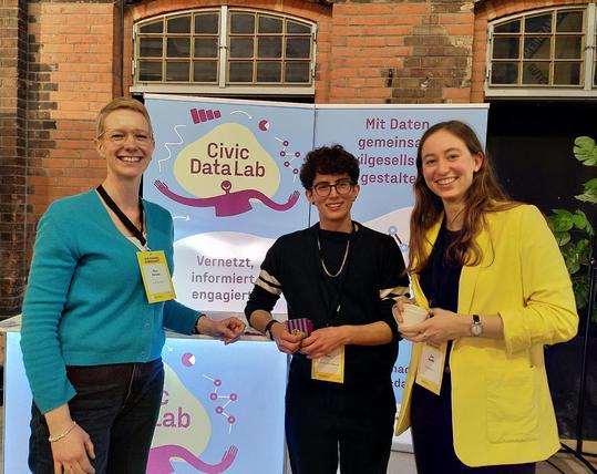Drei Mitglieder des Civic Data Lab Team an ihrem Stand auf dem Marktplatz