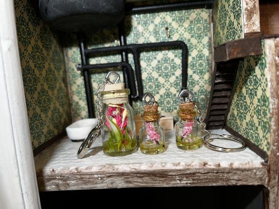 Miniature bottled flowers as keychains photographed in a dollhouse