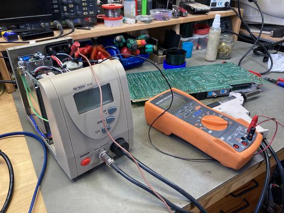 My ZD-915 desoldering station with the lid open and my multimeter connected to the pump motor contacts on my workbench. A C64 PCB is visible in the background and several tools are scattered around (as usual).