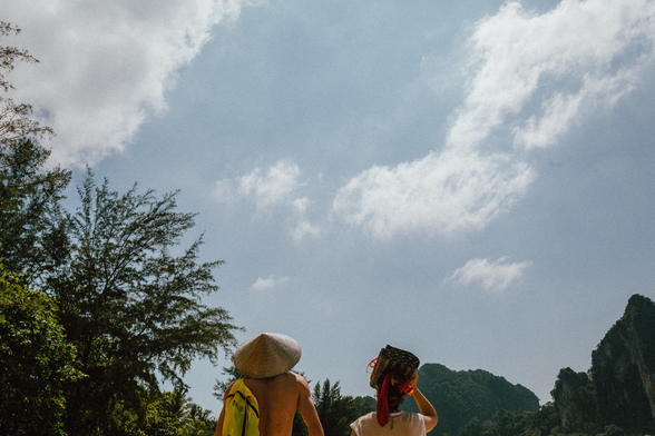 Two people walking on Railay Beach in Thailand on a sunny day.