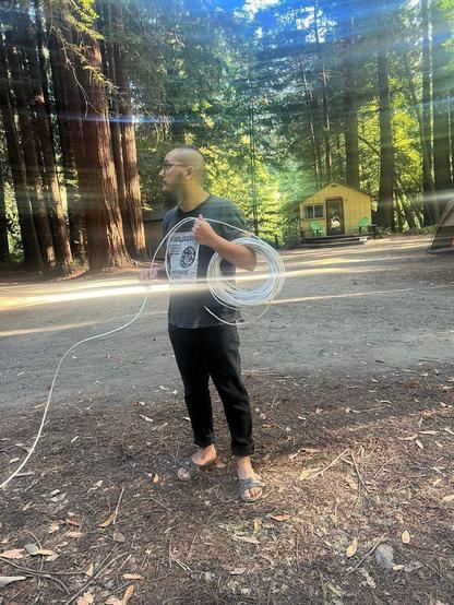fauno at DWeb Camp 2024, holding a cable. Photo credits: kiado cruz