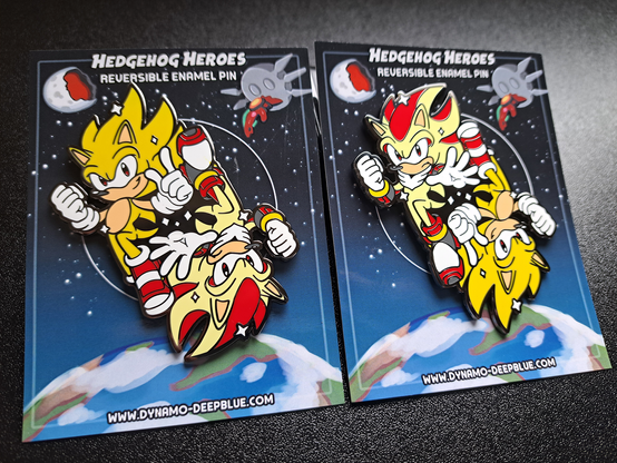 A photograph of two enamel pins with a design featuring Super Sonic and Super Shadow. The pin design itself shows Sonic and Shadow floating opposite each other, each with one leg raised and bent, in a yin-yang sort of fashion, with a heroic air. Because of this, the design is reversible, so one can face right side-up while the other faces upside-down. The photo shows one pin facing one direction and a second pin beside it facing the opposite direction.

Sonic is looking toward the viewer with a confident smirk while Shadow looks toward the viewer with a stoic frown. They both have their right hand clenched into a fist, but Sonic is doing his signature finger wag while Shadow holds hand out forward with his fingers splayed, with their left hands. Sonic is also wearing his SOAP shoes from Sonic Adventure 2 rather than his regular shoes.

The backing card design has a starry space background with Earth in view towards the bottom. The Eclipse Cannon floats in the upper right hand corner of the image, with the Biolizard/Finalhazard attached to the front of the structure. The upper left shows the moon razed in half by the Eclipse Cannon.