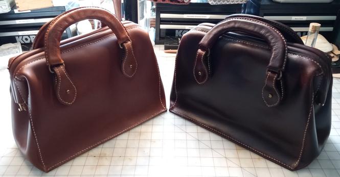 Two tan bags with hinged gladstone type closures. One bag is tan and one bag is mahogany. The bags are identical in design except the handles on the tan bag are placed half an inch higher to make it slightly easier to grab.  The bags are twelve inches long at the base and eleven inches long at the top. This is barely discernible because of the way the bags close. They are eight inches deep and six inches tall. The handles are made out of vegetable tanned leather in coordinating shades. The handles are attached with leather tabs that close with Chicago screw buttons. They are hand stitched with contrasting tan waxed thread.