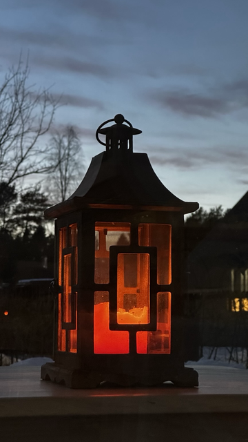 A candle light outside in dusk. Red warm light in contrast to the cool light from the sky.