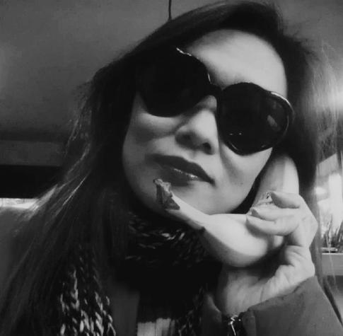 A black and white close-up of me wearing large, dark sunglasses and a patterned scarf. Holding a banana to my ear as if using it as a telephone