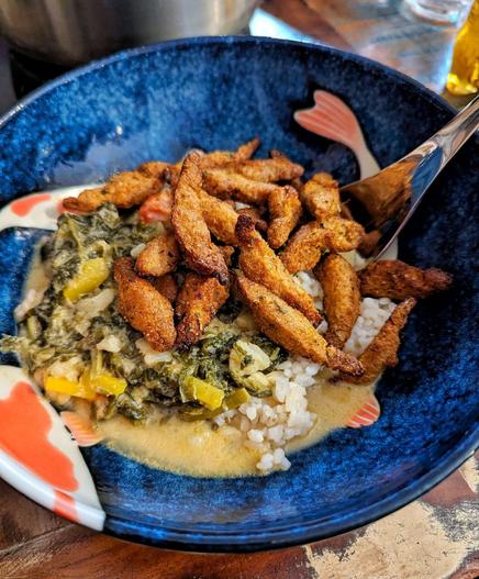 Blaue Schale mit Koi-Motiv auf Esstisch. In der Schale: Sticky Reis, eine cremige, beige Sauce mit grünem und gelbem Gemüse und oben auf knusprige ,braungolden gebackene, große Sojastücke.