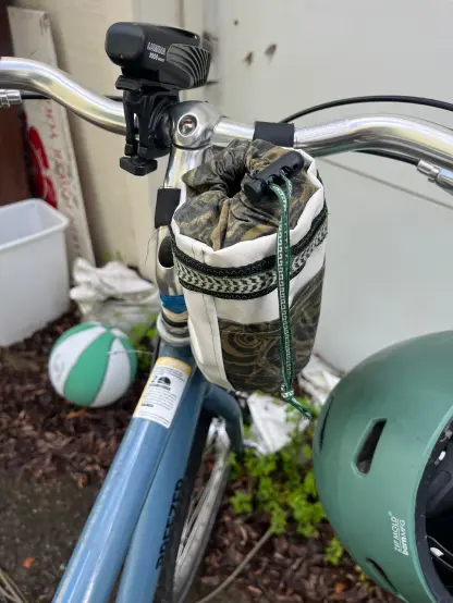A white stem bag with green and black accents  attached to a blue and silver bike