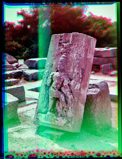 A carved relief fragment of a destroyed temple. In color, but with some light leaks creating weird color effects.