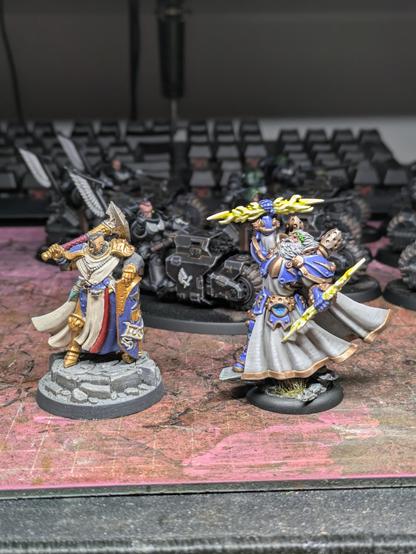 A female Stormcast eternal in gold armour, with shield and hammer, next to Warmachine zeus like character with blue armour and lightning bolts in hand