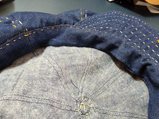 Interior closeup of a dark blue denim newsboy cap with a light blue linen lining.
