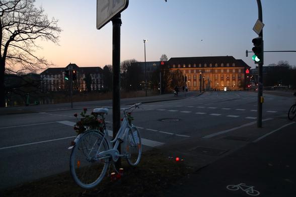 Ein weiß lackiertes Ghostbike steht angekettet an der Kreuzung Martensdamm-Jensendedamm in Kiel. Die Sparkasse im Hintergrund.