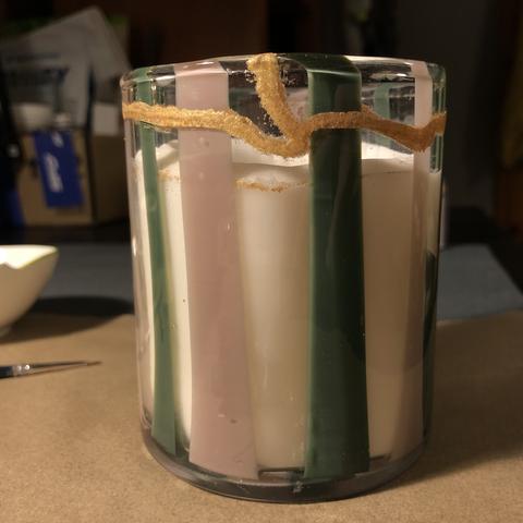 Candle in a glass with lilac and green stripes. Two pieces of the rim were glued back on, and are shining with messy line of gold mica. Glass is particularly hard to work with and it shows.