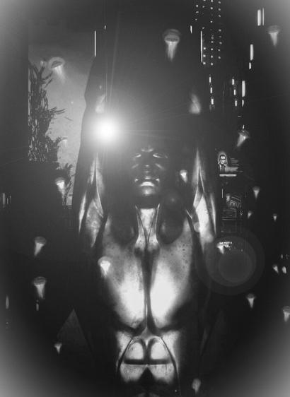 A black and white capture of the head and torso of a statue with raised arms.