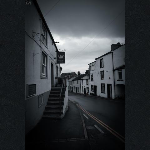 Empty village street of old terrace properties, with heavy sky above. Flat muted colour profile
