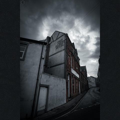 Empty village street of old terrace properties, with heavy sky above. Flat muted colour profile