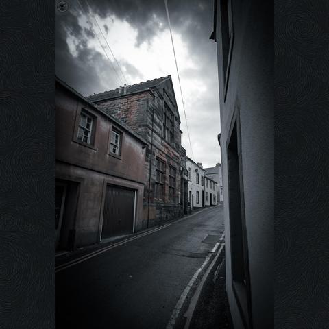 Empty village street of old terrace properties, with heavy sky above. Flat muted colour profile