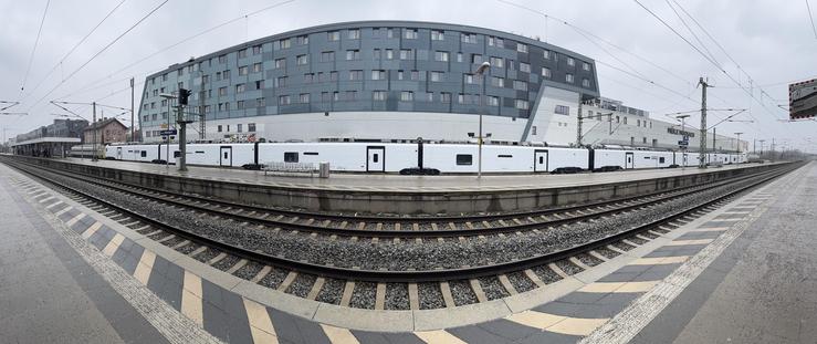 Panorama eines Regionalzuges eingewickelt in weißes Plastik am Bahnhof Moosach