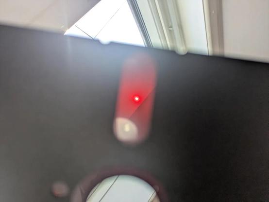 An out of focus 5¼" floppy disk held up to a rooflight with an equally out of focus blob of pink light in the centre of the disc window which you can just about convince yourself isn't circular