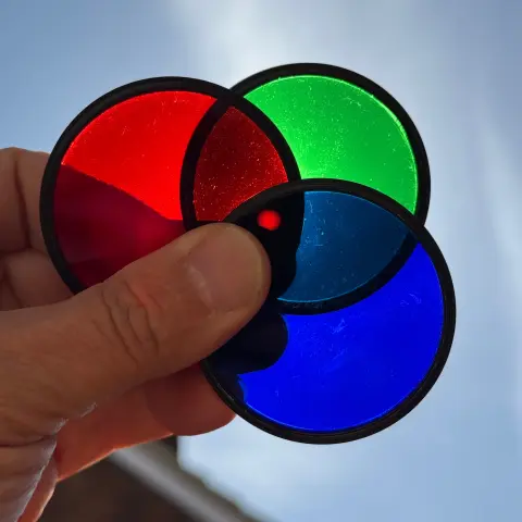 Holding the three pop filters up to the sun, the red and green and blue separated with a small overlap in the middle where the sun is shining through darkness (my phone focussing on the filters though, not the sun)