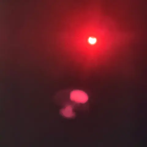 Putting all three filters over the lenses of my iPhone 15 Pro Max, it turns everything too dark for it to properly focus, but there’s a small blobby out of focus reddish shot of the sun with a chunk taken out of the top
