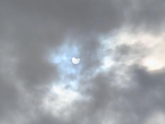 El eclipse solar parcial del 29 de marzo de 2025. Se ve el sol entre unas grises nubes eclipsado por la parte superior derecha como si estuviera sonriendo.