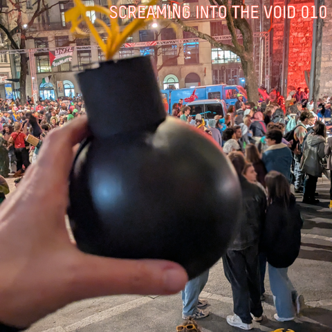 A small bomb prob made from a balloon is held by a hand, in the background the final assembly with the burning of the "bonhomme hiver" the winter guy