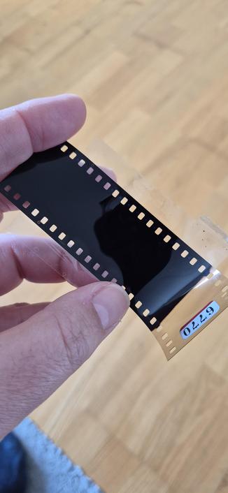Hand hält schwarzen Diafilm, der als Filter verwendet wurde