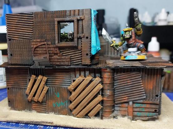 Other side, which is mostly walls and some windows, boarded up on the bottom floor. Some graffiti and two orks waving guns and weapons