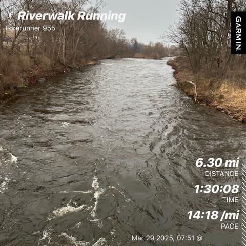 A river flows through a partly wooded area on a gray day. Overlay text indicates a running workout titled "Riverwalk Running" with stats: 6.30 miles distance, 1:30:08 time, and 14:18 per mile, March 29 @ 07:51 (8:53/km pace 10.15 km distance)