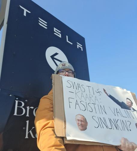 Mielenosoittaja pitää kylttiä Raision Tesla Storen sisäänkäynnillä. Kyltissä lukee:"Swastikaara: fasistin valinta. Sinunkin?"