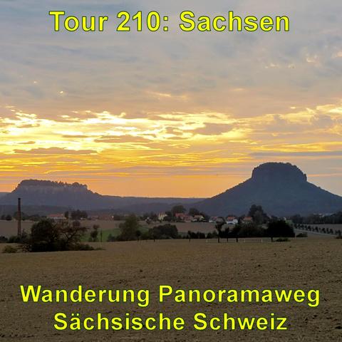 Blick auf die Festung Königstein auf einem Berg im Abendlicht. Darunter eine Landschaft mit Feldern und wenigen Gebäuden. Der Himmel ist mit gelb-orangen Wolken gemustert.