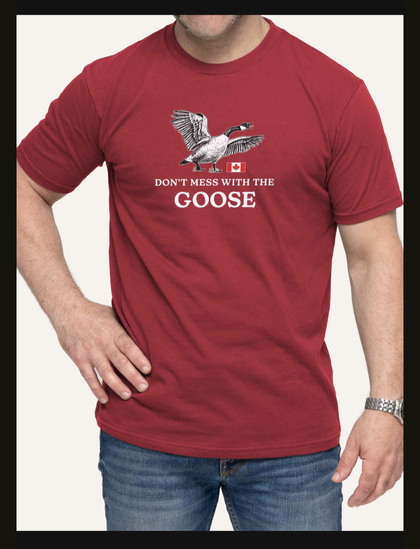 Red t-shirt says 

DON'T MESS WITH THE
GOOSE

Above the text is an angry Canada Goose defending a small flag of Canada.