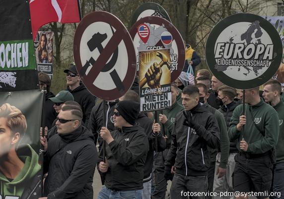 nazi-demozug. es werden schilder getragen ("europa eidgenossenschaft", durchgestrichenes hammer und sichel oder "löhne rauf, mieten runten") ein fascho zeigt den "white-power-gruß"