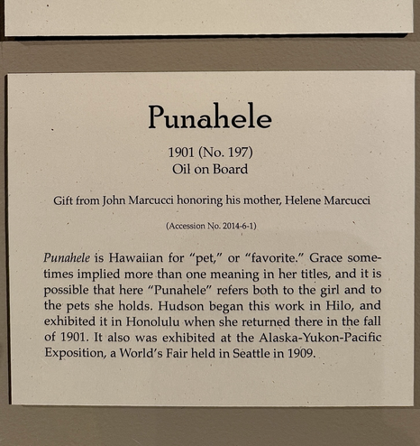 photo of the gallery label: “Punahele 1901 (No. 197) Oil on Board Gift from John Marcucci honoring his mother, Helene Marcucci (Accession No. 2014-6-1) Punahele is Hawaiian for "pet," or "favorite." Grace sometimes implied more than one meaning in her titles, and it is possible that here "Punahele" refers both to the girl and to the pets she holds. Hudson began this work in Hilo, and exhibited it in Honolulu when she returned there in the fall of 1901. It also was exhibited at the Alaska-Yukon-Pacific Exposition, a World's Fair held in Seattle in 1909.”