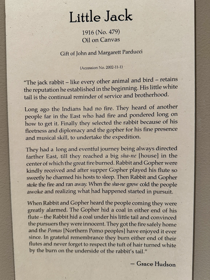 photo of the gallery label: “The jack rabbit - like every other animal and bird - retains the reputation he established in the beginning. His little white tail is the continual reminder of service and brotherhood. Long ago the Indians had no fire. They heard of another people far in the East who had fire and pondered long on how to get it. Finally they selected the rabbit because of his fleetness and diplomacy and the gopher for his fine presence and musical skill, to undertake the expedition. They had a long and eventful journey being always directed farther East, till they reached a big sha-ne housel in the center of which the great fire burned. Rabbit and Gopher were kindly received and after supper Gopher played his flute so sweetly he charmed his hosts to sleep. Then Rabbit and Gopher stole the fire and ran away. When the sha-ne grew cold the people awoke and realizing what had happened started in pursuit. When Rabbit and Gopher heard the people coming they were greatly alarmed. The Gopher hid a coal in either end of his flute - the Rabbit hid a coal under his little tail and convinced the pursuers they were innocent. They got the fire safely home and the Pomas Northern Pomo peoples] have enjoyed it ever since. In grateful remembrance they burn either end of their flutes and never forget to respect the tuft of hair turned white by the burn on the underside of the rabbit's tail." - Grace Hudson”