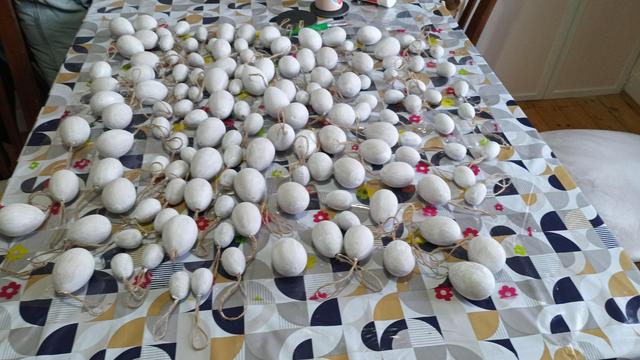All the eggs have been painted white and  are laid out across the table on a sheet of clear plastic