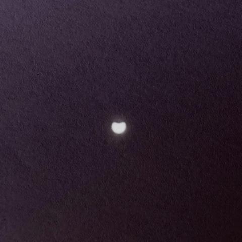 An image of the sun projected onto a piece of paper through a pinhole during the partial solar eclipse of 29 March 2025, with a "bite" taken out of the top of the sun's disc of light. The projection has been flipped to reflect the correct orientation of the eclipse.