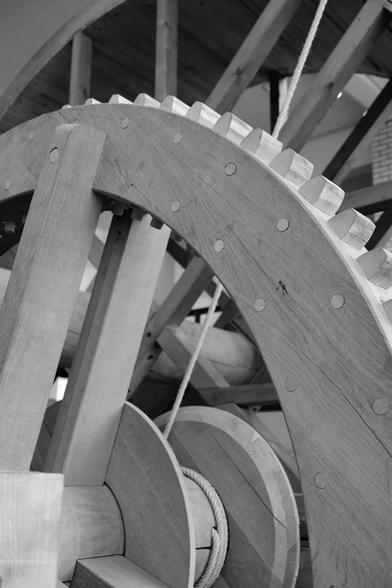 Black and white picture of a reconstruction of an old crane with gears and treadmill.